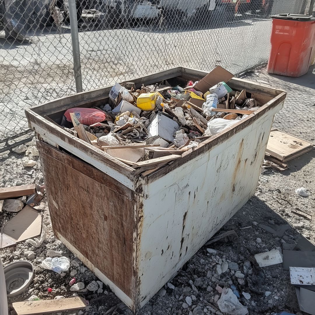 A full white metal dumpster overflowing with various construction debris.